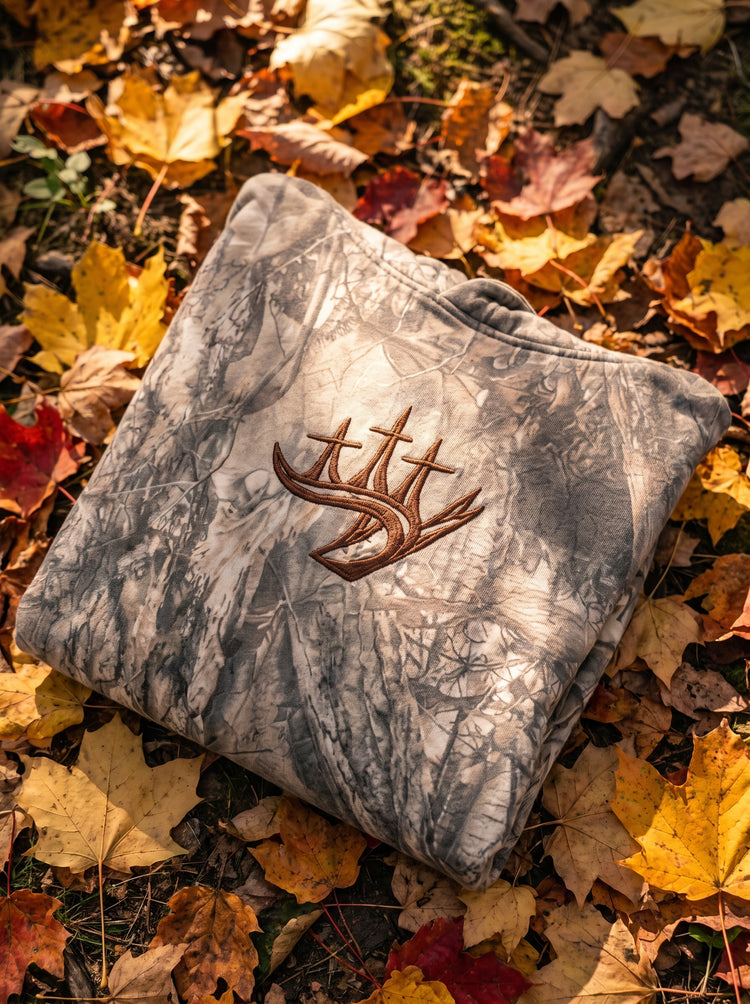 Folded Covenant Camo hoodie with embroidered antler crest on autumn leaves