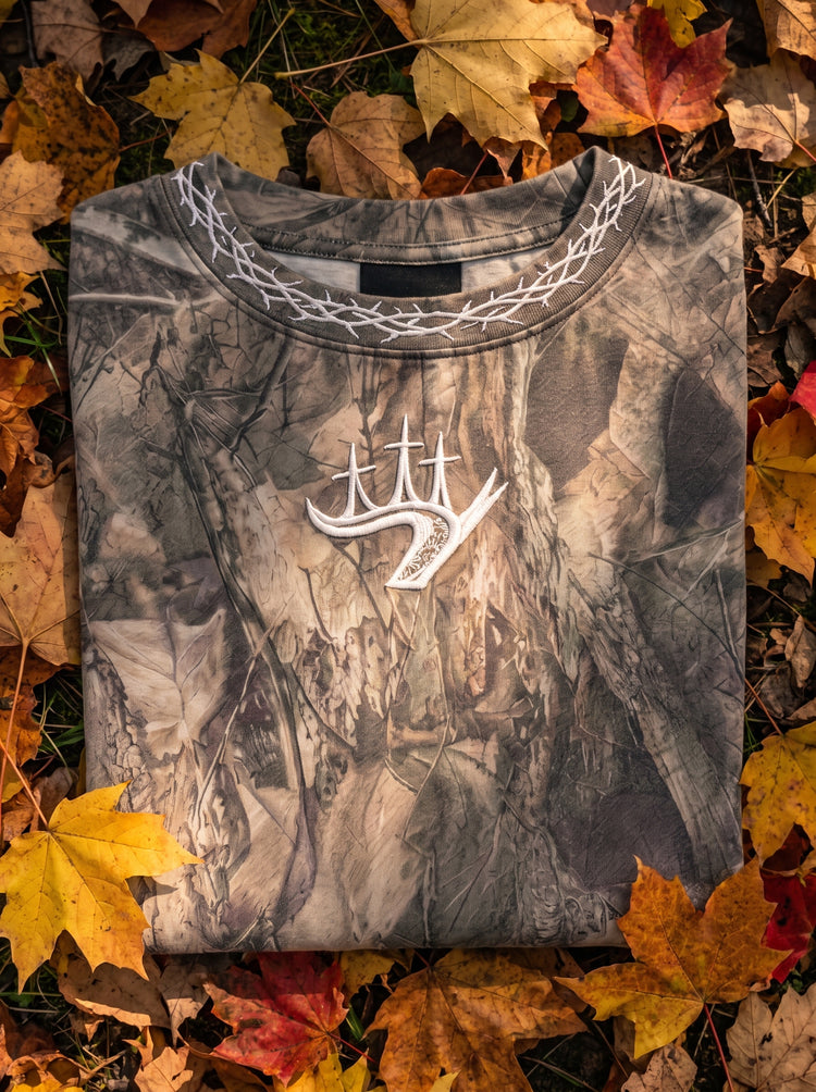 Folded Covenant Camo tee with embroidered antler crest on autumn leaves